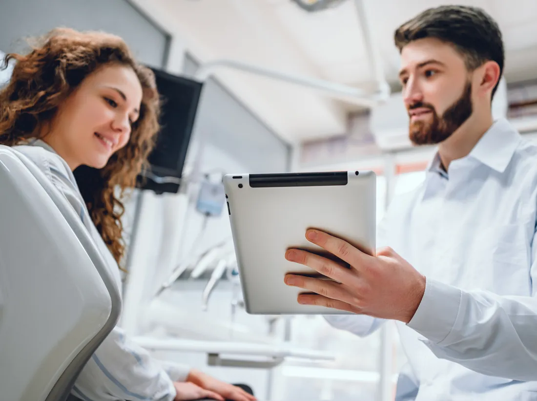 A dentist showing a patient her treatment plan on a tablet